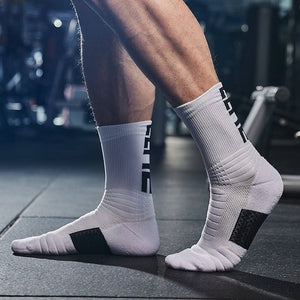 Athlete wearing white sports socks with black heel patches, standing in a gym with equipment in the background.