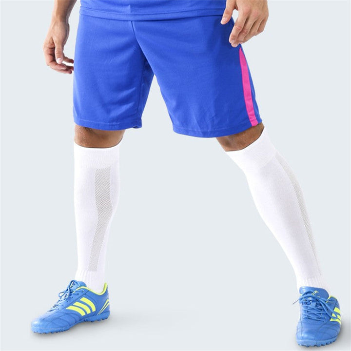 A person wearing white knee-high sports socks, blue shorts with a pink stripe, and blue athletic shoes.