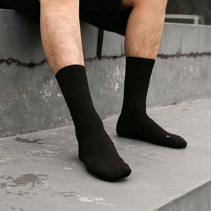 A person wearing black crew socks sitting on a concrete ledge with legs partially visible.