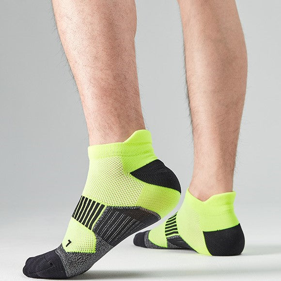 A person wearing black and lime green athletic ankle socks.