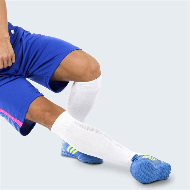 Close-up of a person in blue sports attire with pink detailing, wearing white knee-high sports socks and blue soccer shoes.