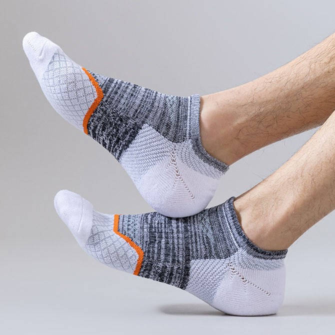 Crossed feet in white and grey socks with bold orange stripes, on a neutral background.