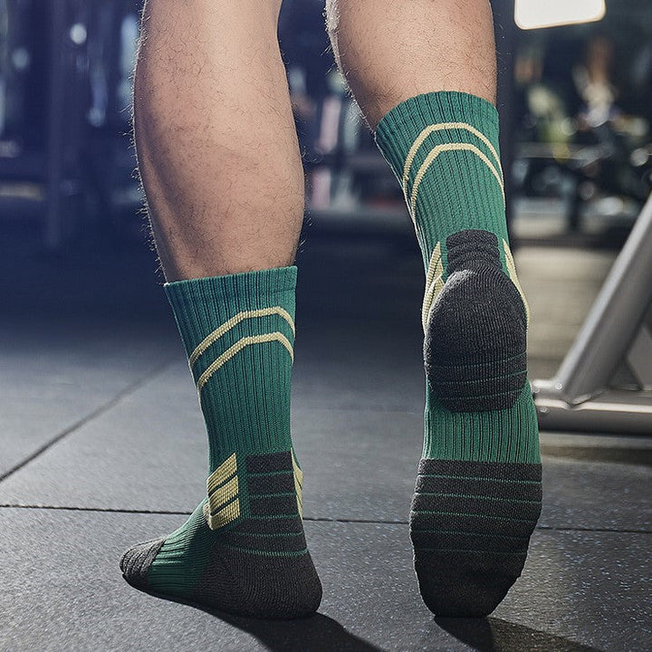 A pair of green and gold basketball socks worn by an athlete standing in a gym.