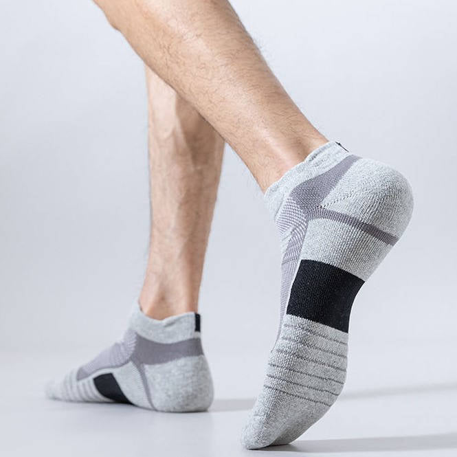 Person wearing grey sports socks with black and white accents, shown from the side.