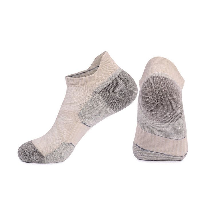 Pair of light beige sports socks with gray reinforcements isolated on a white background.