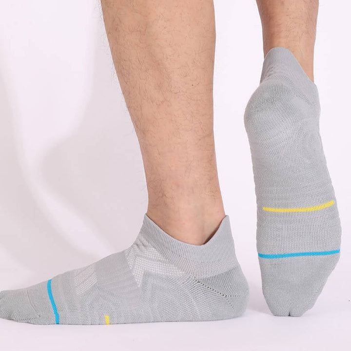 Person wearing light grey no-show socks with blue and yellow accents, viewed from the side and back.