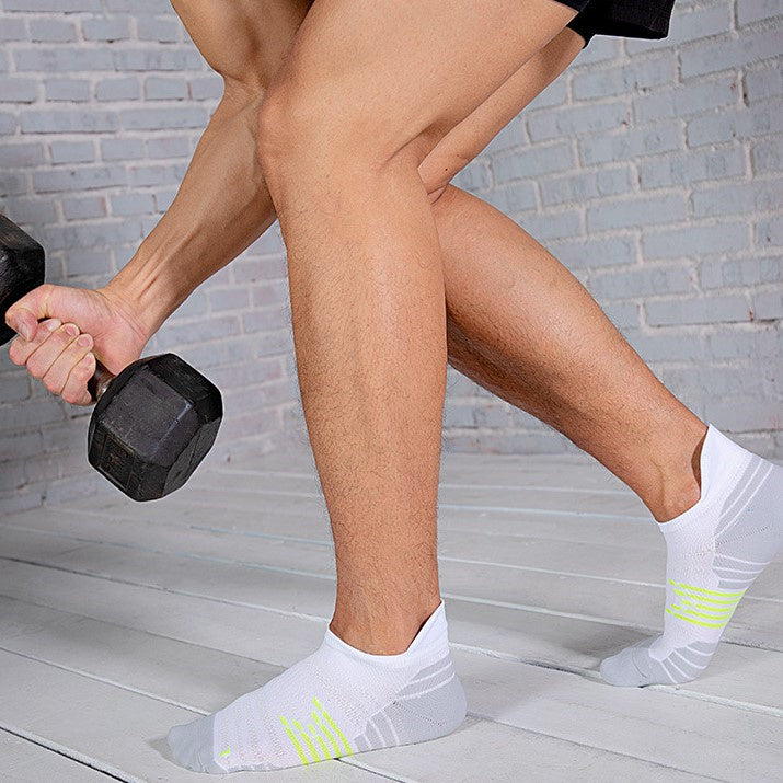 Man lifting dumbbells while wearing white ankle socks with neon yellow accents.