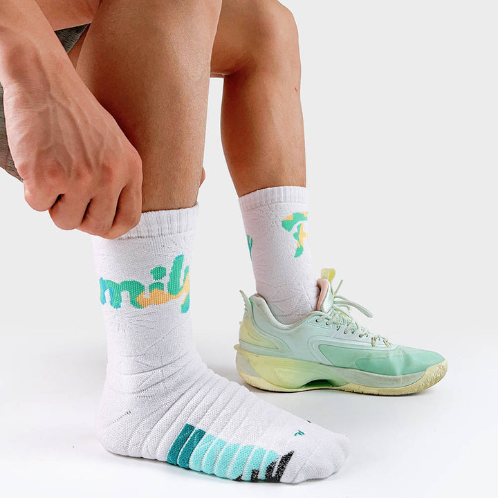 Person pulling up white socks with teal 'fun' text and stripes, wearing a matching pastel green sneaker.