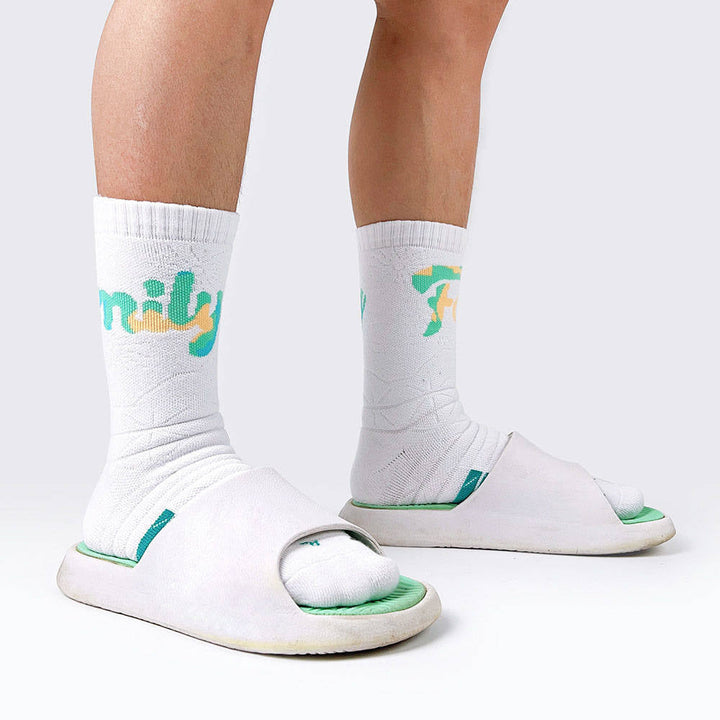 Person standing in white socks with green 'fun' lettering, complemented by white sandals with green trim.