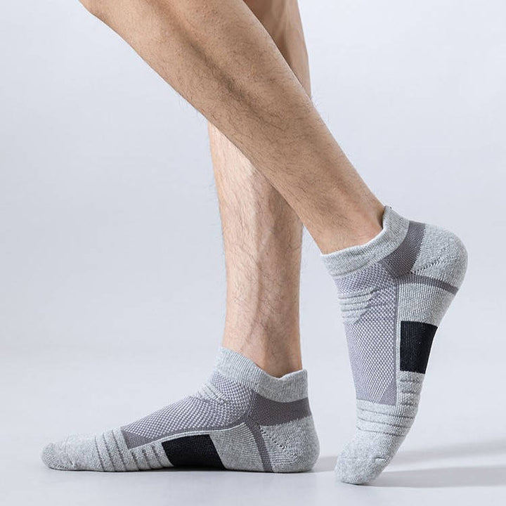 Individual wearing textured grey ankle socks with black heel and toe patches, posed on a light background.