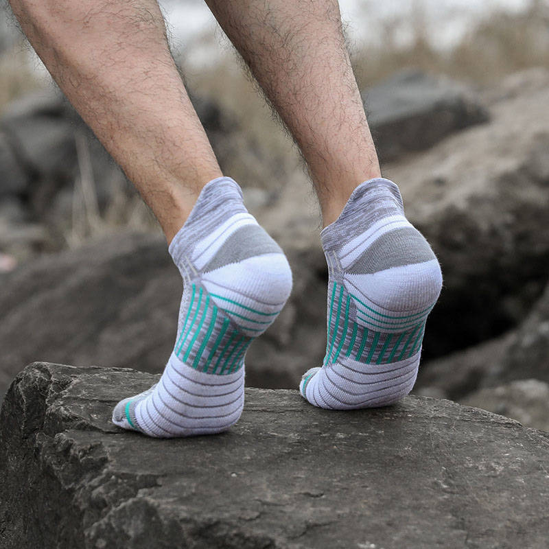 Person wearing white and gray socks with green details standing on a rock.