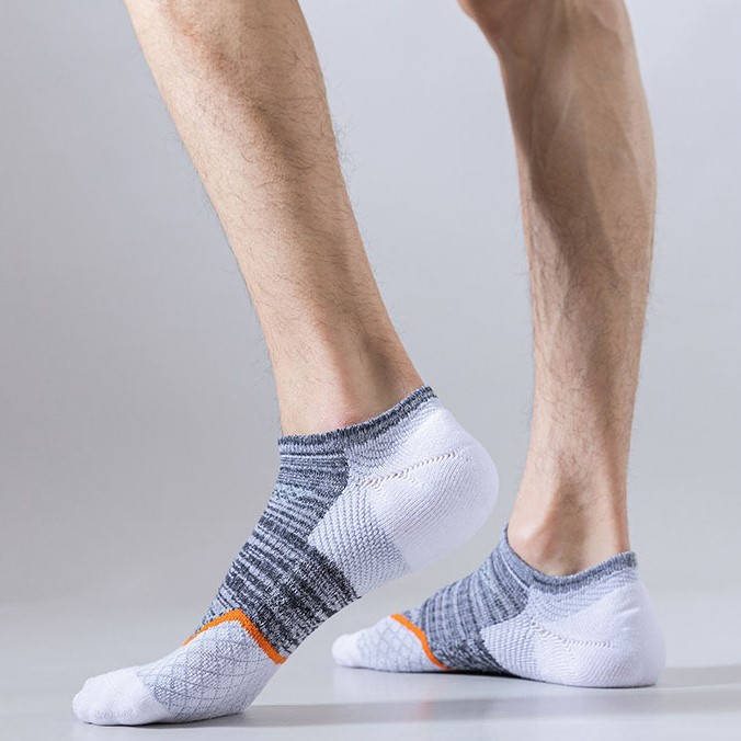 Person wearing white and grey athletic socks with orange detailing, side profile view.