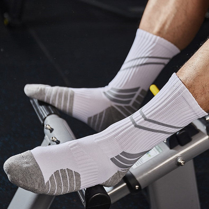 A pair of white basketball socks with grey accents, worn by an athlete exercising on gym equipment.